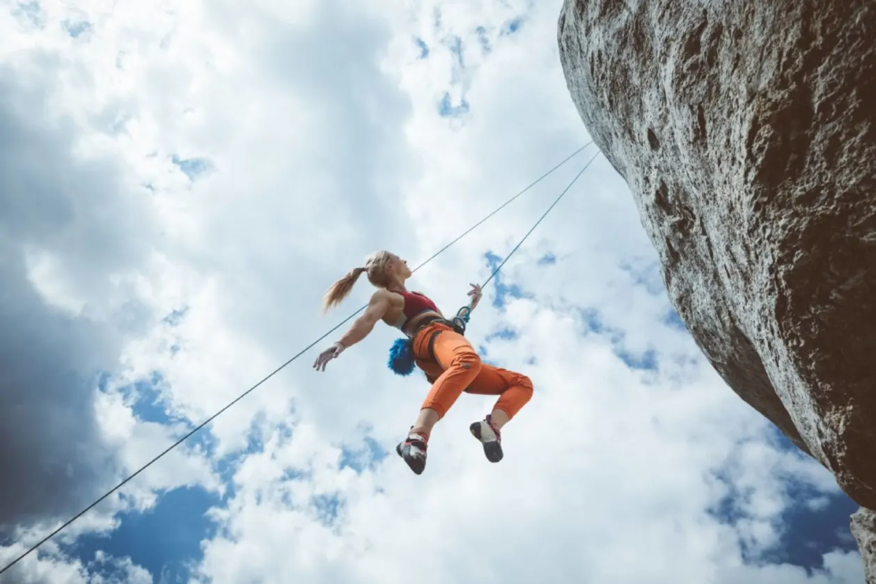 Woman hanging on rope while climbing on cliff
